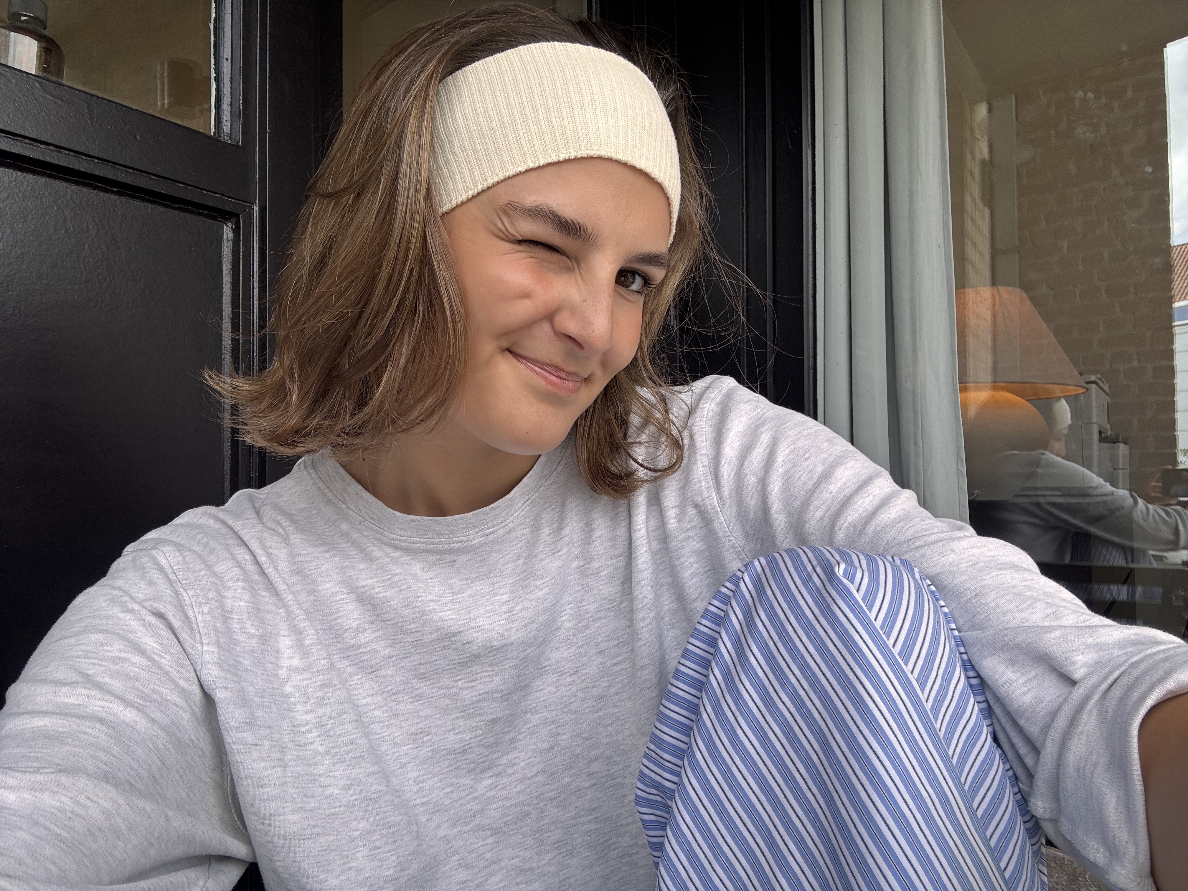The founder of Smooch Studio in a doorway, headband on, mid-wink