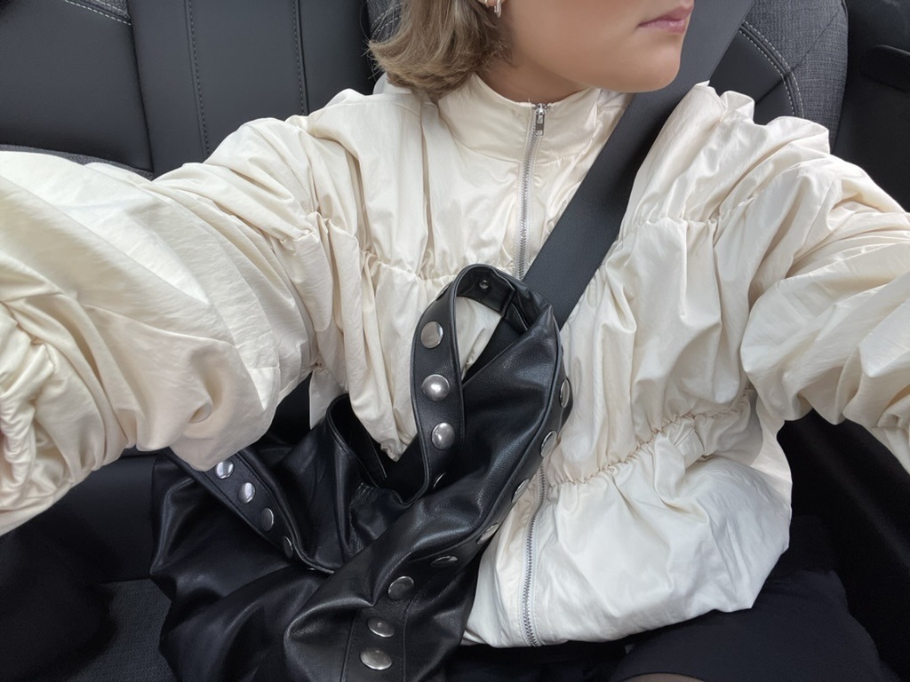 Close-up of the cream jacket and studded leather bag